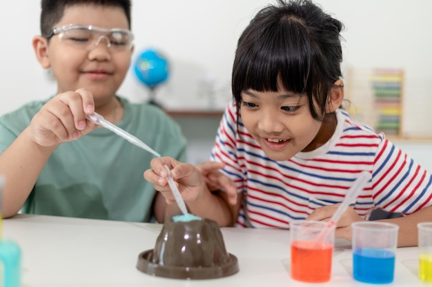 Enfants répétant et observant un projet de laboratoire scientifique à la maison le volcan de bicarbonate de soude et de vinaigre