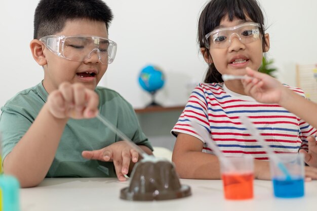 Enfants répétant et observant un projet de laboratoire scientifique à la maison le volcan de bicarbonate de soude et de vinaigre