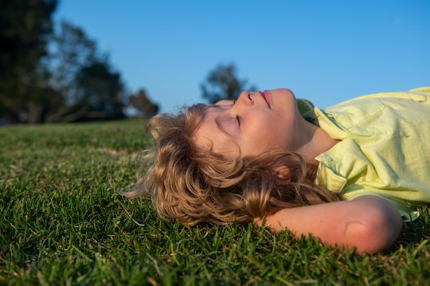 Enfants rêvant Enfant jouant dans la prairie Heureux enfant caucasien en bonne santé avec allongé sur le fond du champ d'herbe Petit enfant dans un bel environnement vert Incroyable enfants heureux en plein air