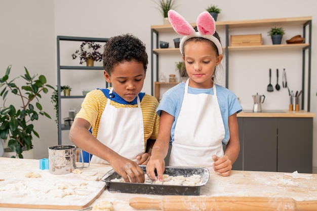 Les enfants roulent la pâte pendant la cuisson des pâtisseries maison