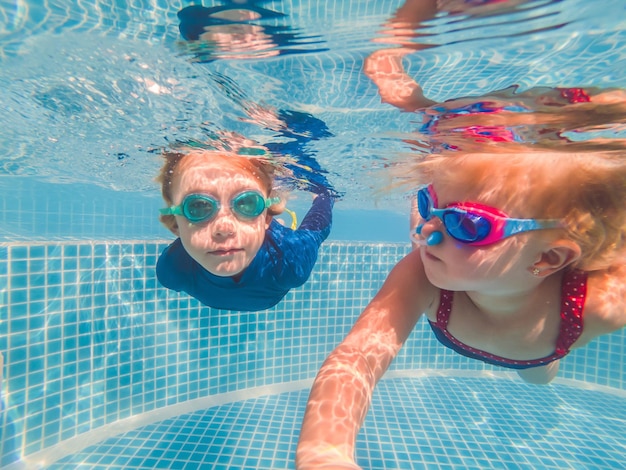 Enfants s'amusant à jouer sous l'eau dans la piscine pendant les vacances d'été