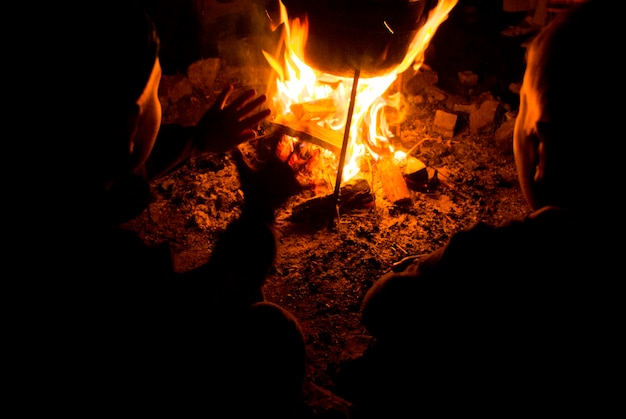 Les enfants s'assoient autour du feu de camp la nuit