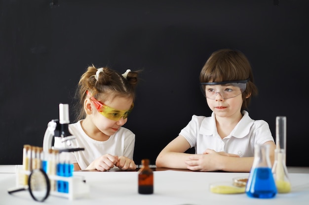 Enfants scientifiques Des écoliers du laboratoire mènent des expériences Garçon et fille expérimentent avec un microscope