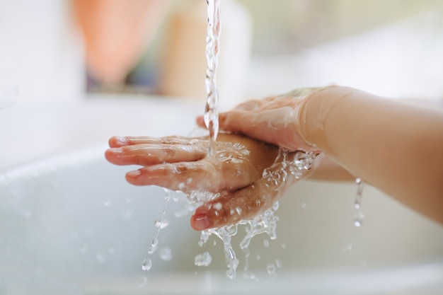 Les enfants se lavent les mains avec du savon liquide et de l'eau pour la prévention de l'infection à Covid-19 ou à coronavirus