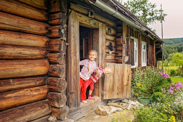 Enfants se reposant à la porte de la vieille maison en bois pendant les vacances d'été, concept de voyage respectueux de l'environnement