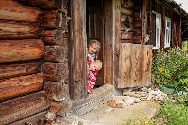 Enfants se reposant à la porte de la vieille maison en bois pendant les vacances d'été, concept de voyage respectueux de l'environnement