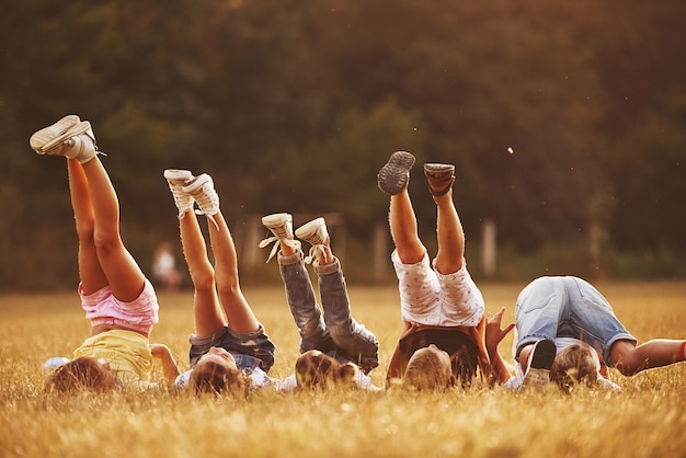 Les enfants se reposent ensemble sur le terrain pendant la journée ensoleillée. Lever les jambes.