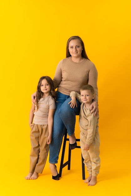 Les enfants se tiennent à côté de leur mère et regardent la caméra Portrait en studio