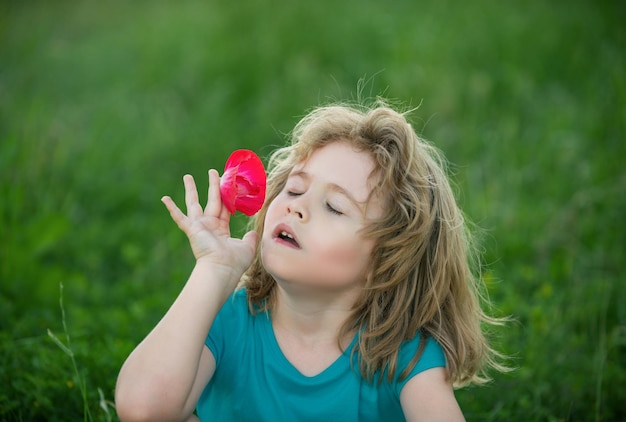 Enfants sentant des fleurs bouchent la tête d'un enfant mignon dans le parc naturel d'été