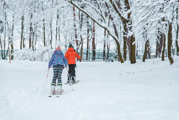 Enfants skiant dans le parc enneigé de la ville