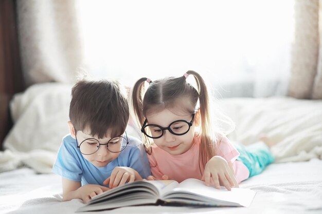 Les enfants sont allongés sur le lit à côté du nouveau-né, petite soeur. Les émotions des enfants.