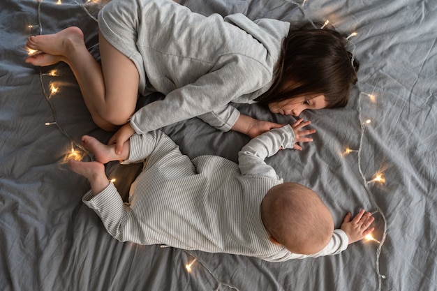 Les enfants sont allongés sur un lit gris entouré des lumières de Noël.