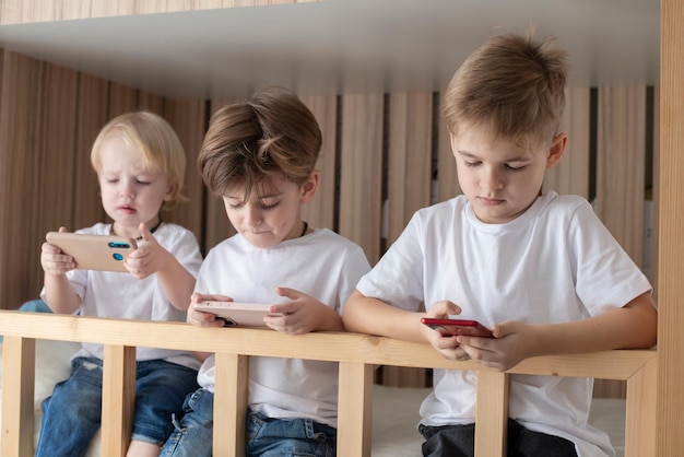 les enfants sont assis sur le lit utilisent le téléphone s'ignorent jeux Internet et communication virtuelle