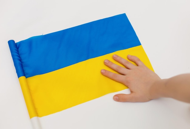 Les enfants sont contre la guerre La main de l'enfant sur le drapeau de l'Ukraine sur fond blanc