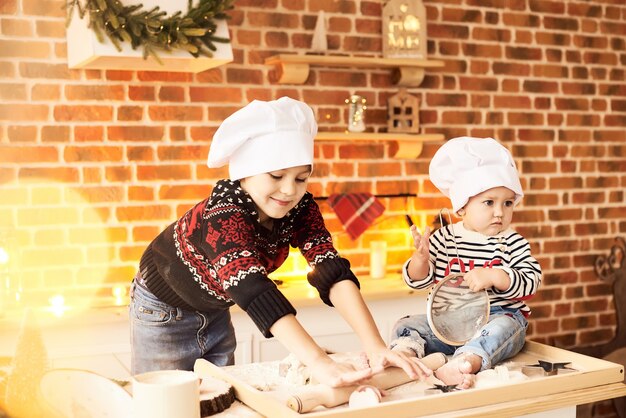 Les enfants sont cuits et jouent avec de la farine et de la pâte dans la cuisine