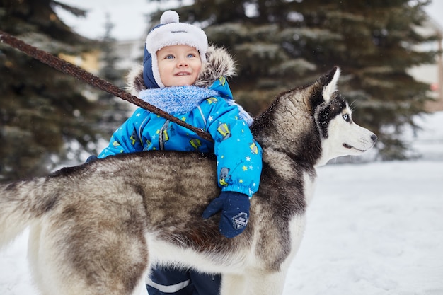 Les enfants sortent et jouent avec un chien husky en hiver