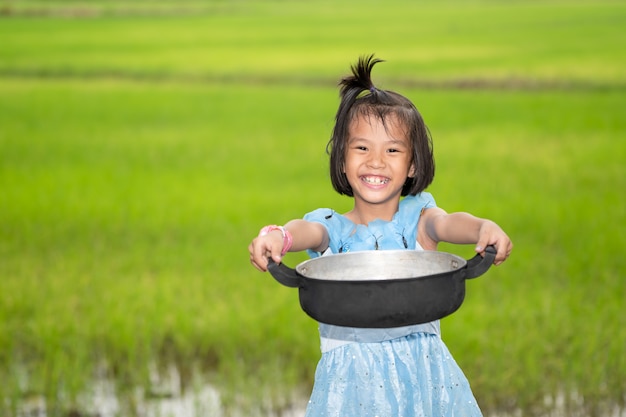 Enfants souriant et tenant le pot de nourriture sur le ciel et les champs de riz flou