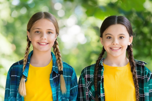 Enfants souriants. bonne fête des enfants. passer du temps et s'amuser ensemble. meilleurs amis d'école. notion d'amitié. les petites filles heureuses portent une chemise à carreaux. mode décontractée pour enfants. bonheur d'enfance.