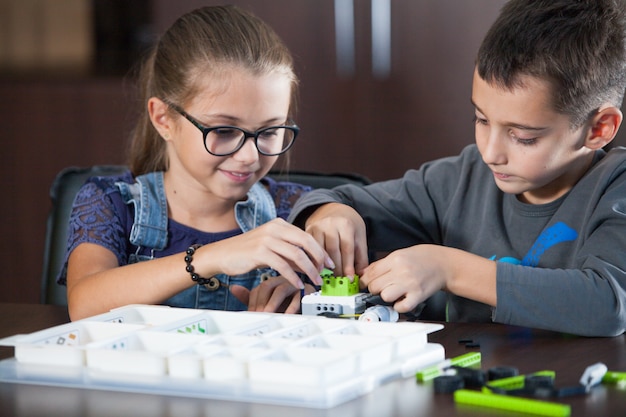 Des enfants souriants et joyeux construisent un constructeur.