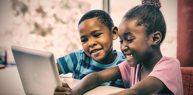 Enfants souriants utilisant une tablette numérique en classe