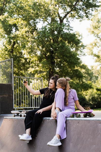 Les enfants sportifs accros au téléphone avec des planches à roulettes et des penny utilisent des téléphones et font des selfies au lieu de patiner et de jouer ensemble Des enfants regardent des smartphones sur une rampe de sport Dépendance au téléphone