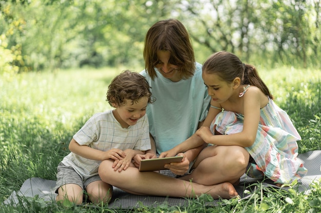 Les enfants avec une tablette à l'extérieur les enfants jouent à des jeux sur le concept de la technologie de la tablette