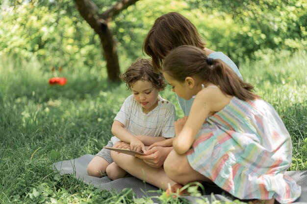 Les enfants avec une tablette à l'extérieur les enfants jouent à des jeux sur le concept de la technologie de la tablette