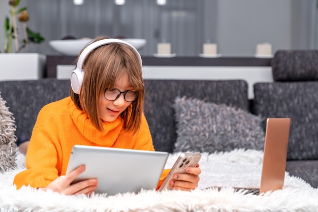 Les enfants et la technologie moderne jouent et étudient à la maison à l'aide d'un smartphone, d'une tablette pour ordinateur portable et d'un casque sans fil