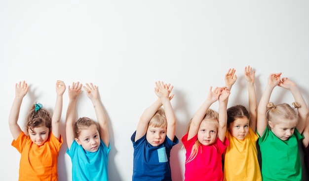 Enfants tenant les mains sur fond de mur blanc