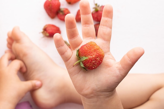 Photo les enfants tiennent les mains de la fraise rouge en haut.