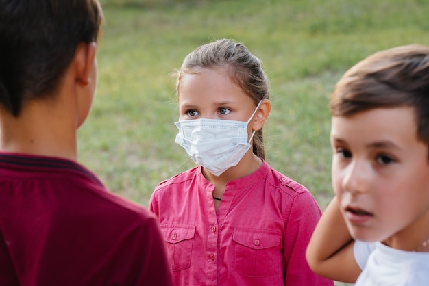 Les enfants traînent dans le parc avec des masques pendant une pandémie.