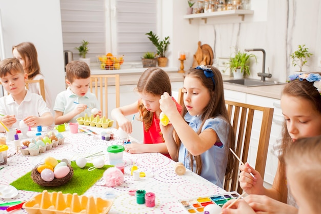 Des enfants très concentrés peignent des œufs. Famille heureuse se préparant pour Pâques, concept de travail d'équipe