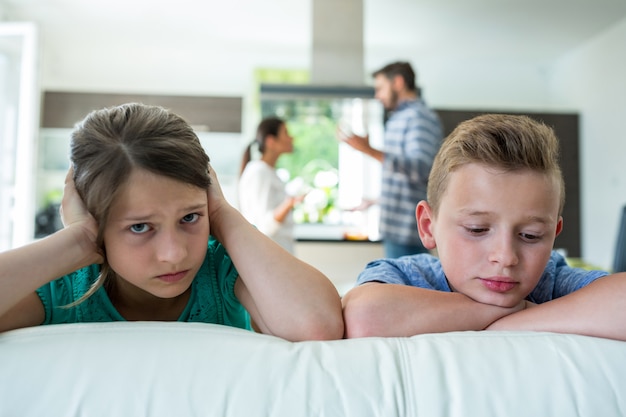 Enfants Tristes S'appuyant Sur Le Canapé Pendant Que Les Parents Se Disputent