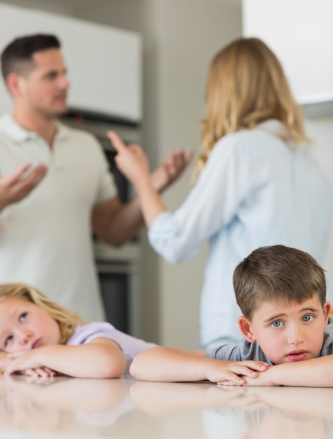 Enfants tristes se penchant sur la table pendant que les parents se disputent