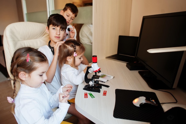 Enfants utilisant un microscope apprenant des cours de sciences à la maison.