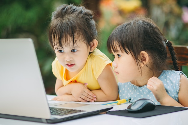 Enfants utilisant un ordinateur portable pour étudier à la maison.