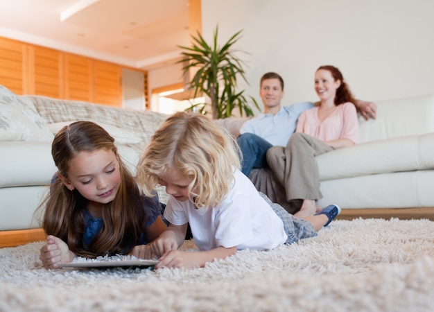 Enfants utilisant une tablette sur le tapis