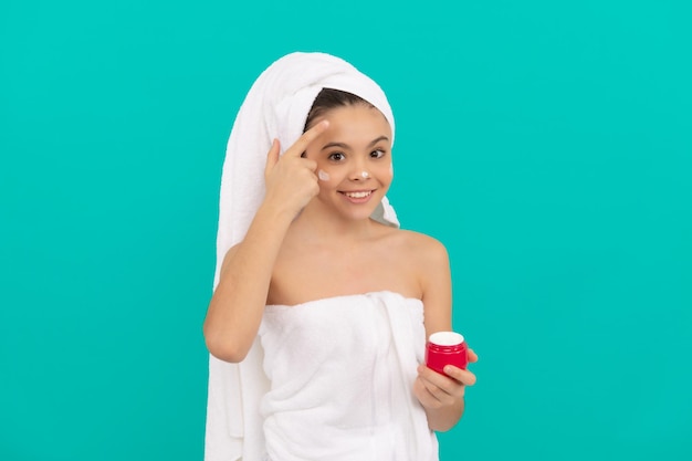 Les enfants utilisent de la crème pour le visage. tween girl tenir le masque capillaire. enfant avec de la crème pour la peau. habitude quotidienne et soins personnels. beauté des soins de la peau. cosmétique de beauté. gommage nettoyant. appliquant. présentant un produit cosmétique pour adolescent.