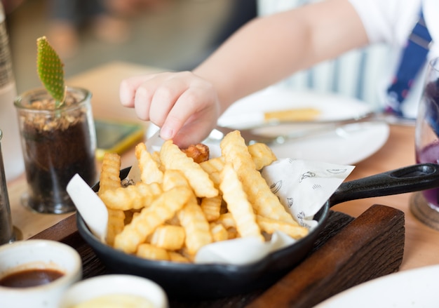 Photo les enfants utilisent sa main prendre frit dans le bol en céramique