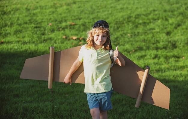 Les enfants volent drôle enfant garçon avec Thumbs up smile porter chapeau de pilote et des lunettes de vol avec un jouet en carton