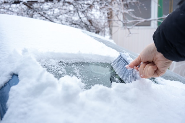 Enlever la neige du pare-brise de la voiture avec une brosse de voiture