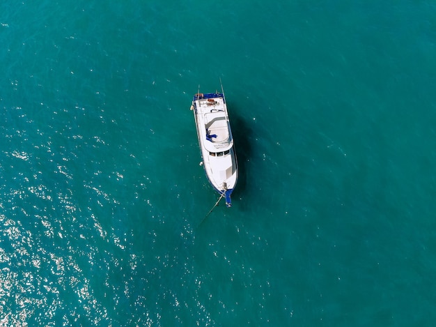 Un énorme yacht blanc navigue seul sur la mer d'un bleu profond, vue de dessus