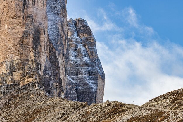 D'énormes montagnes rocheuses connues sous le nom de Tre Cime dans les Alpes italiennes et ciel bleu nuageux