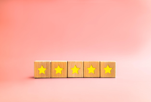 Photo enquête sur les commentaires des clients avec étoile jaune sur cinq blocs de cube en bois sur fond rose pastel avec espace de copie style minimal examen de la note du produit client cinq étoiles satisfaction de l'expérience client