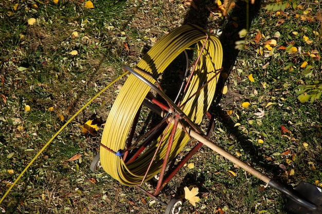 Un enrouleur de tuyau jaune est au sol avec une corde jaune dessus.