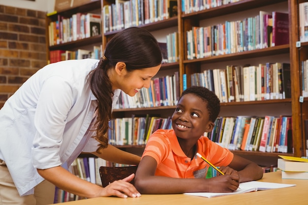 Enseignant Aidant Garçon à Faire Ses Devoirs Dans La Bibliothèque