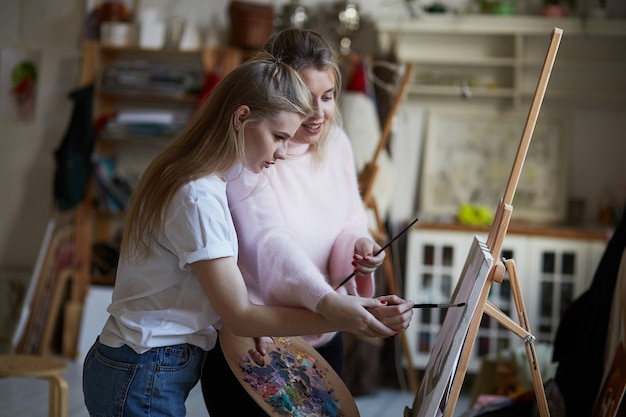 L'enseignant apprend à une jeune fille à peindre sur toile