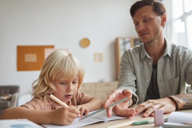 Enseignant assis à la table avec son élève et expliquant hime le nouveau sujet