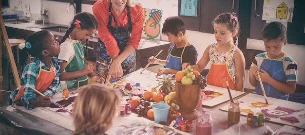 Photo enseignant assistant des écoliers en classe de dessin