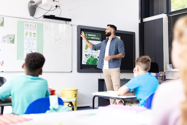 Photo un enseignant caucasien utilisant un tableau blanc dans une salle de classe de l'école primaire diversifiée